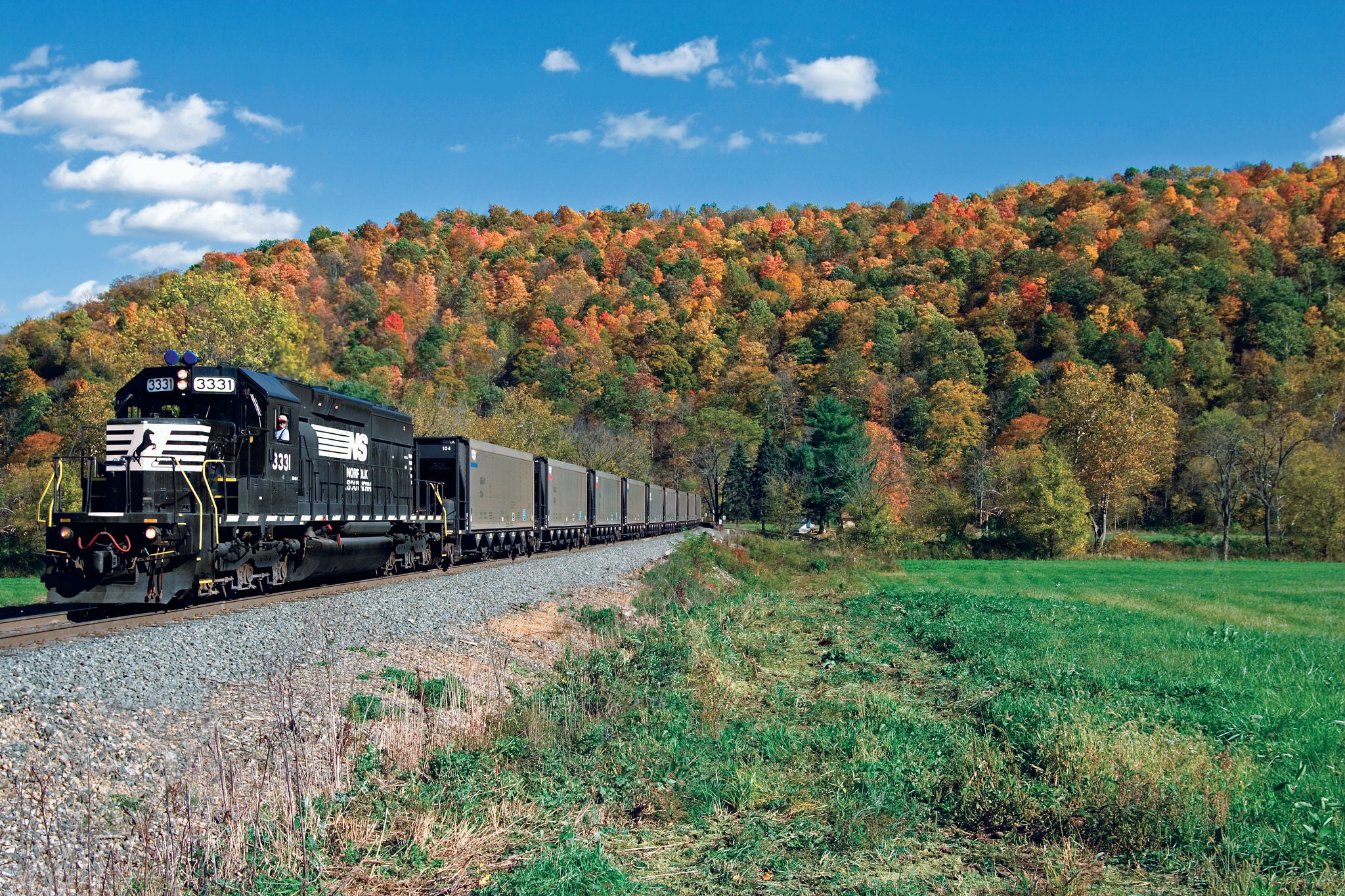 Vibrant fall foliage in Powhatan Point, Ohio, is the backdrop for a Norfolk Southern train as it travels to a coal mine in Belmont County, Ohio. NS owns about 21.000 coal cars, including manual hoppers and gondolas for rotary dump service, high-cubic-capacity coke hoppers, and air-operated quick discharge hoppers.