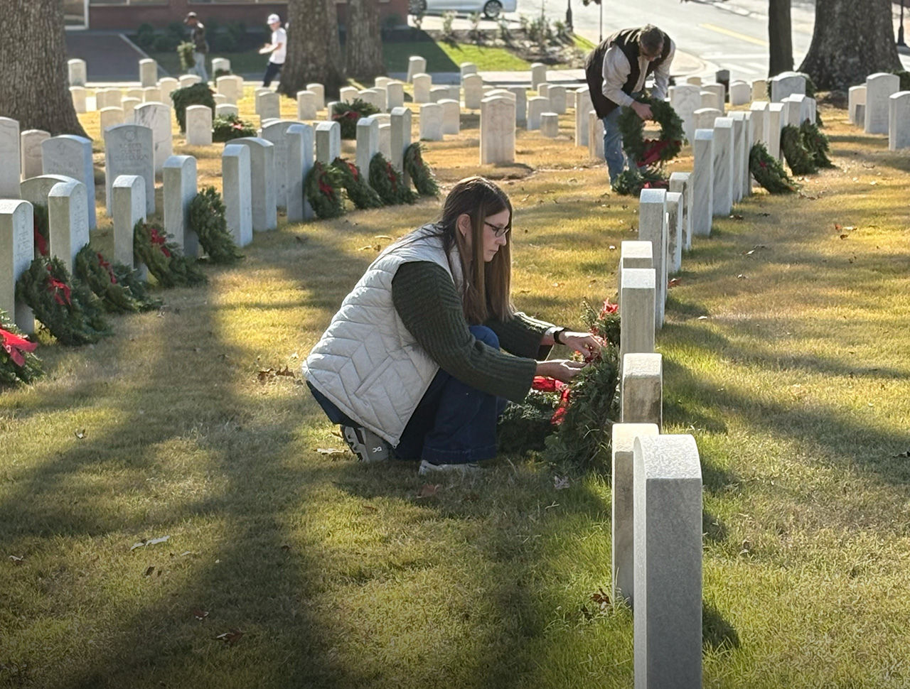 volunteers laying wreaths in cemetery