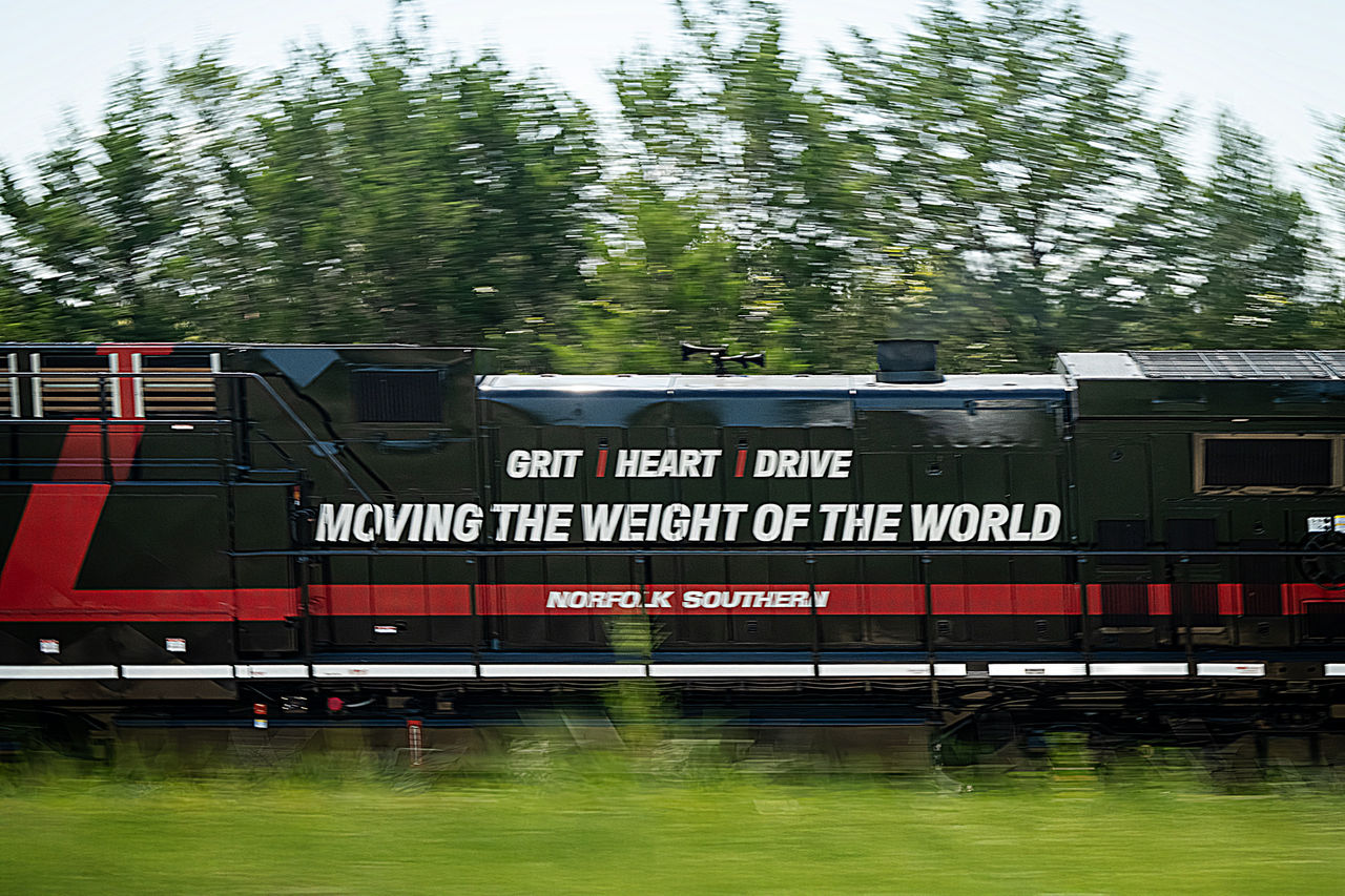 side of moving train with the words: GRIT/HEART/DRIVE - MOVING THE WEIGHT OF THE WORLD